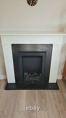 Bio ethanol fire with fuel, glass shield, and white fireplace surround
